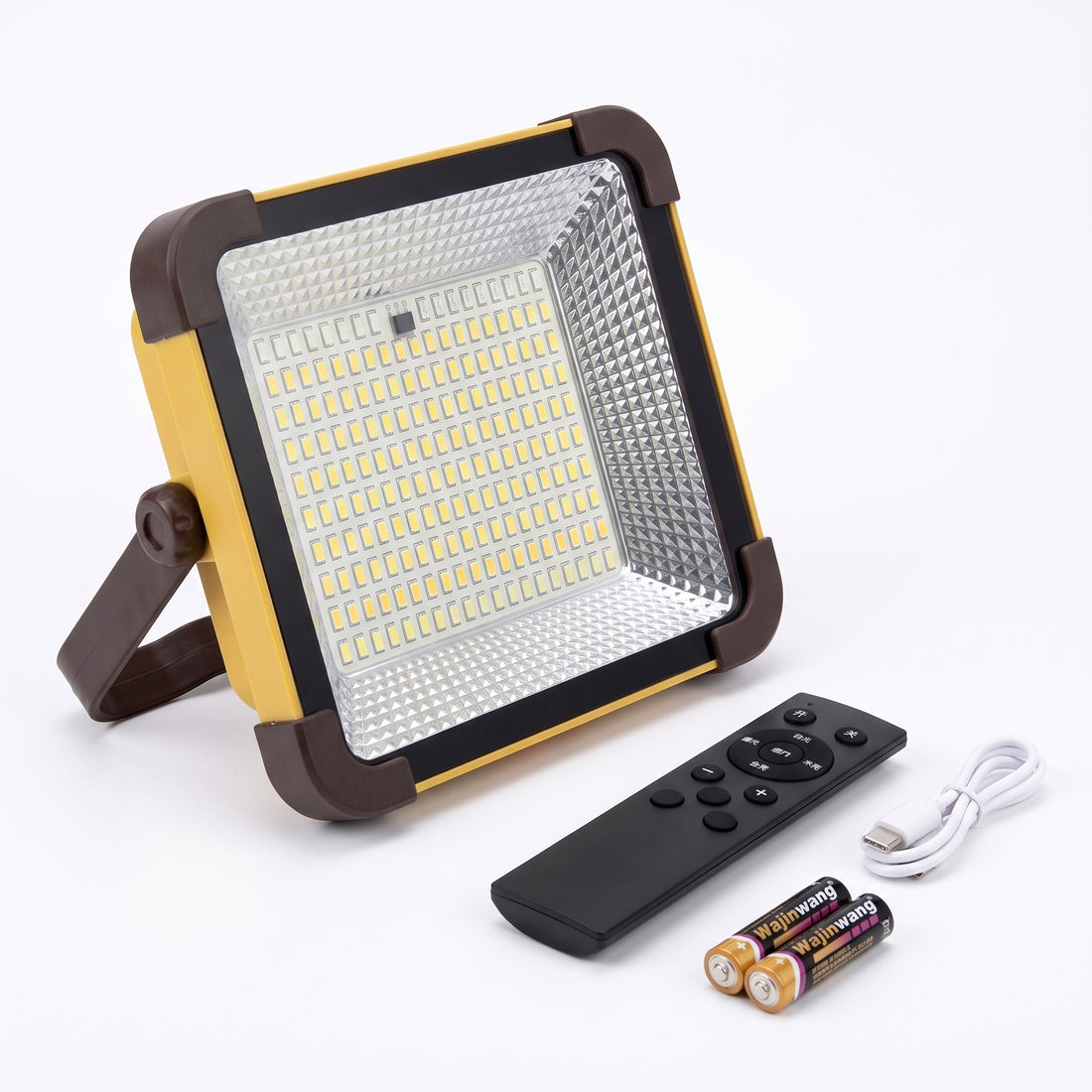 A square LED floodlight with a yellow and dark brown frame, shown with a black remote control, a white USB charging cable, and two batteries on a white background.