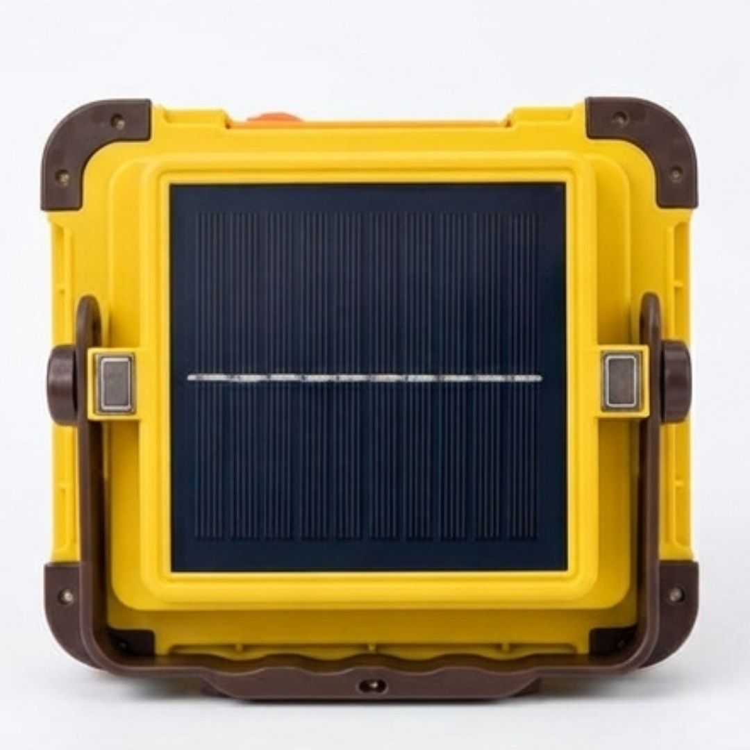 A square LED floodlight with a yellow and dark brown frame, shown with a black remote control, a white USB charging cable, and two batteries on a white background.